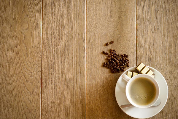 a cup of coffee and beans on a wooden table